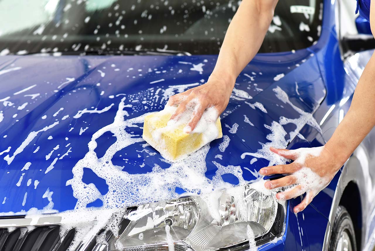 青い車に手洗い洗車をしている様子